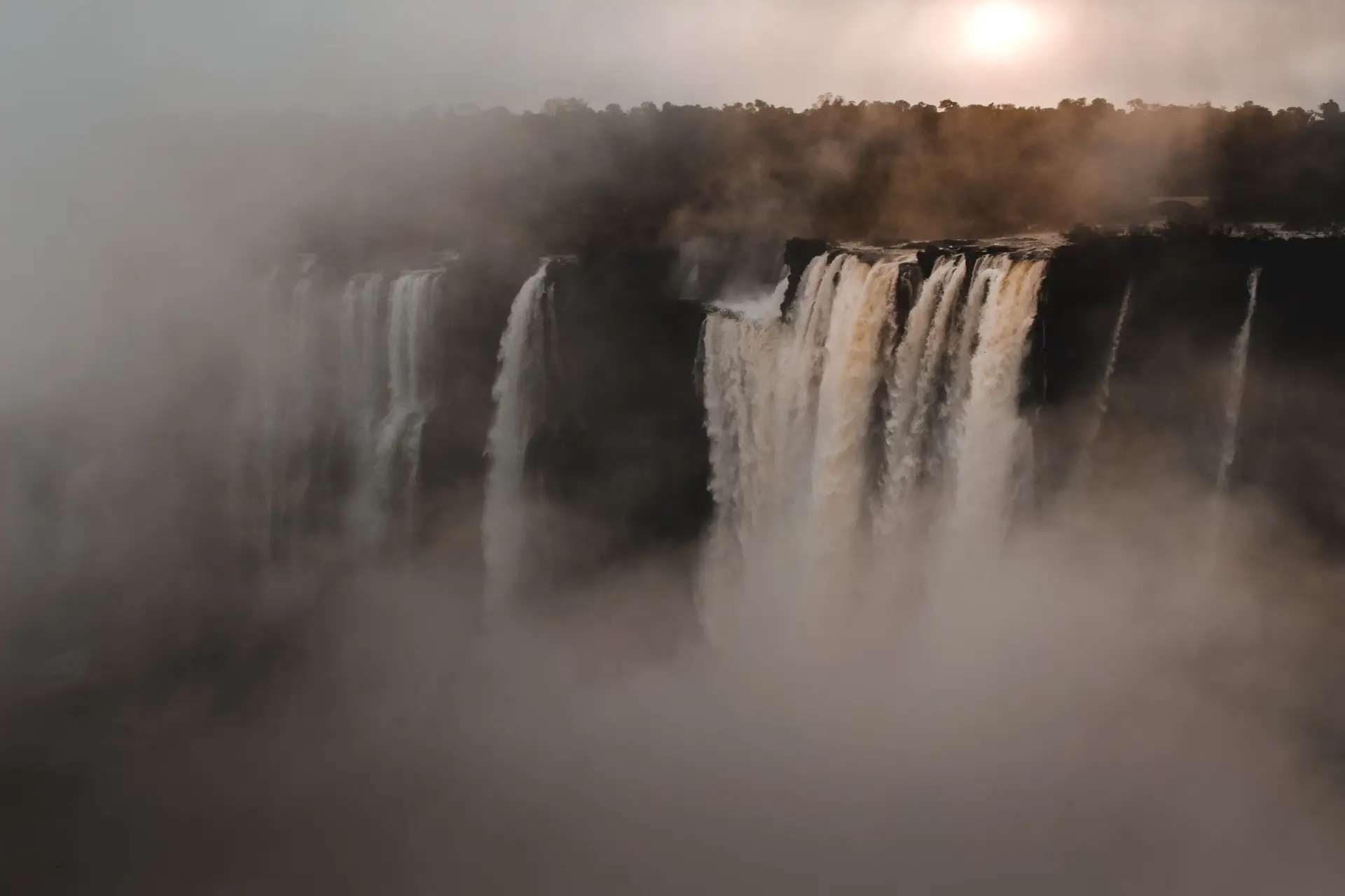 a_large_waterfall_with_fog_and_trees.jpg