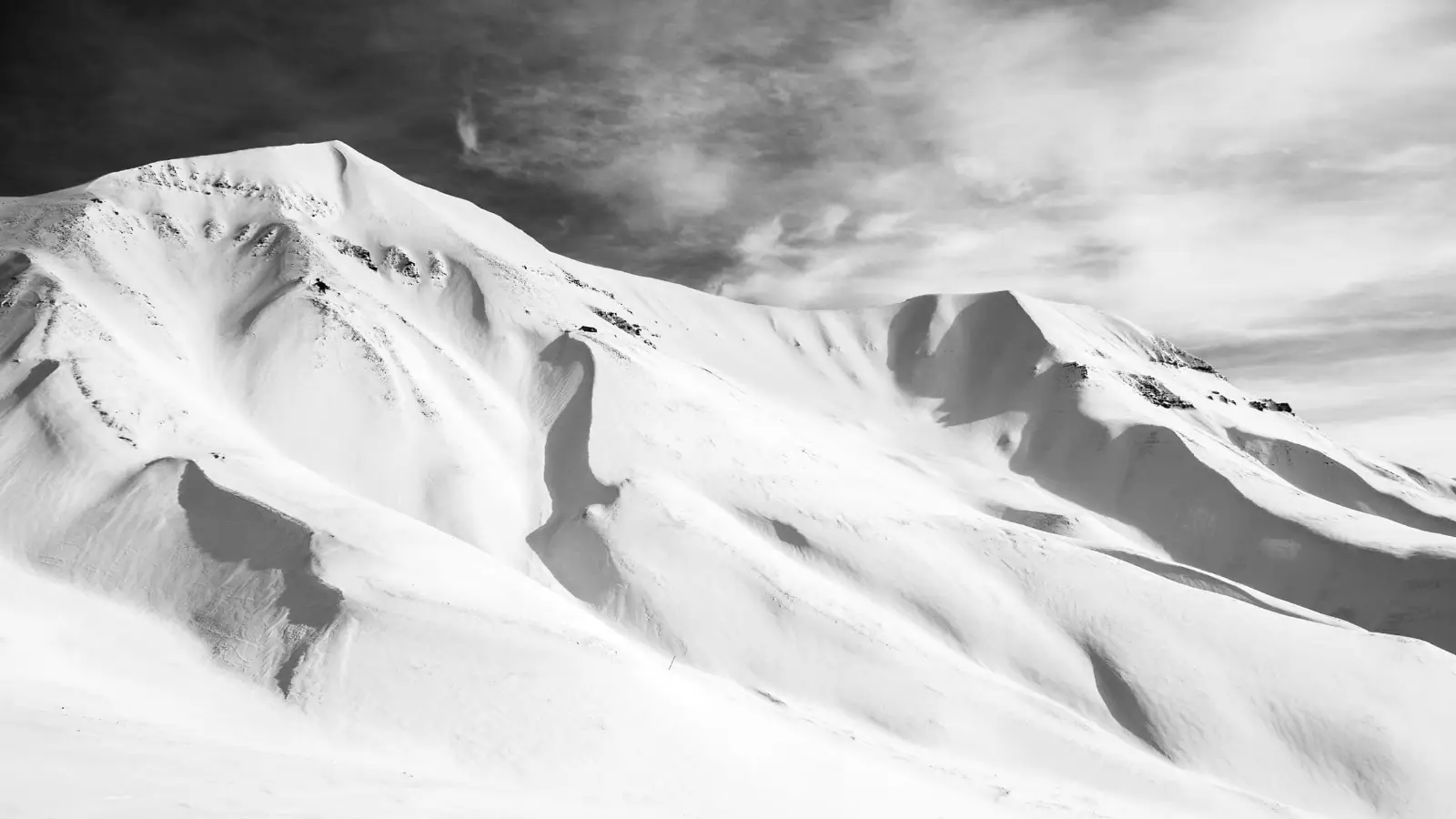 a_snowy_mountain_with_clouds_in_the_sky.jpg