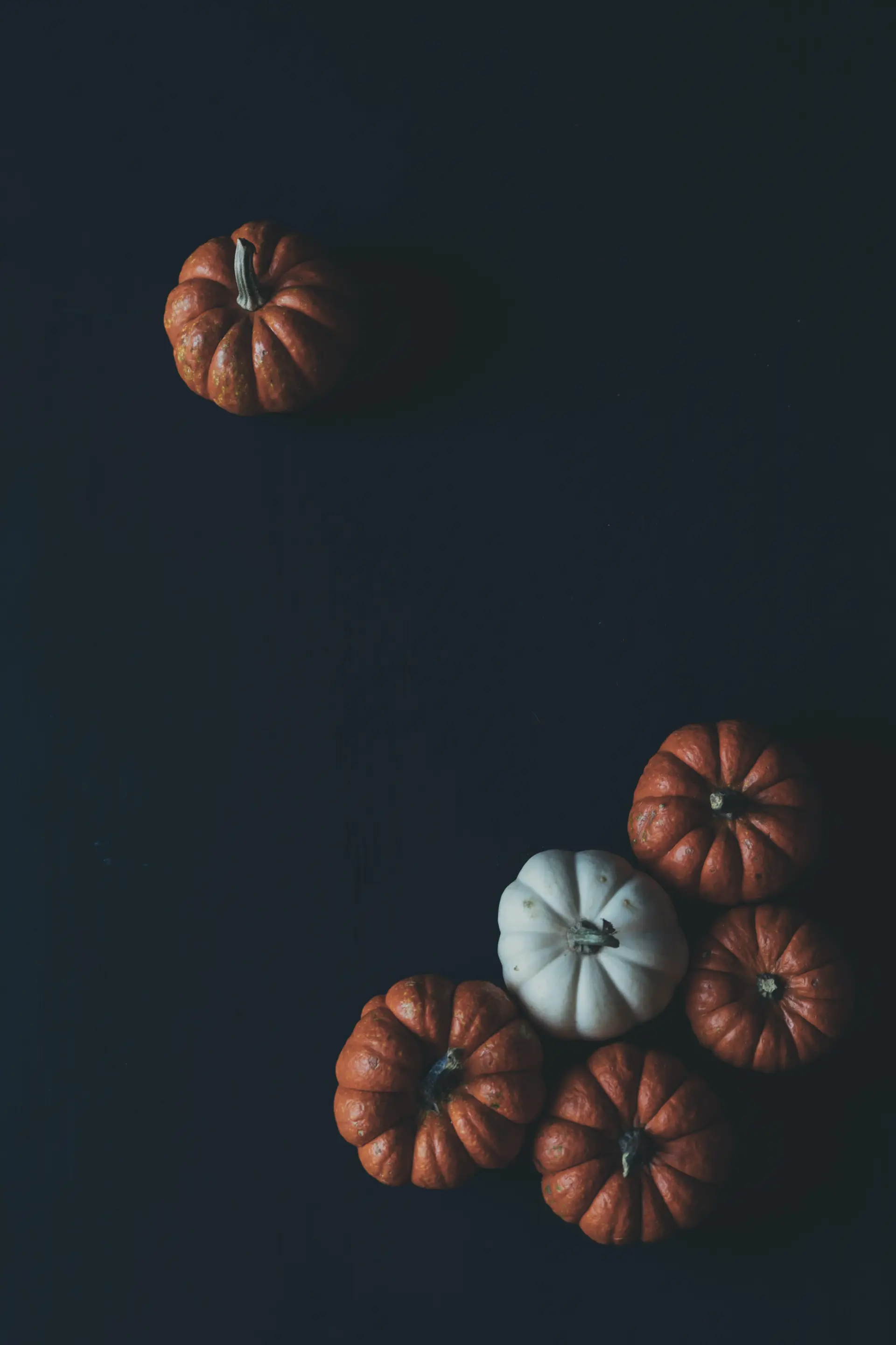 a_group_of_pumpkins_on_a_black_surface.jpg