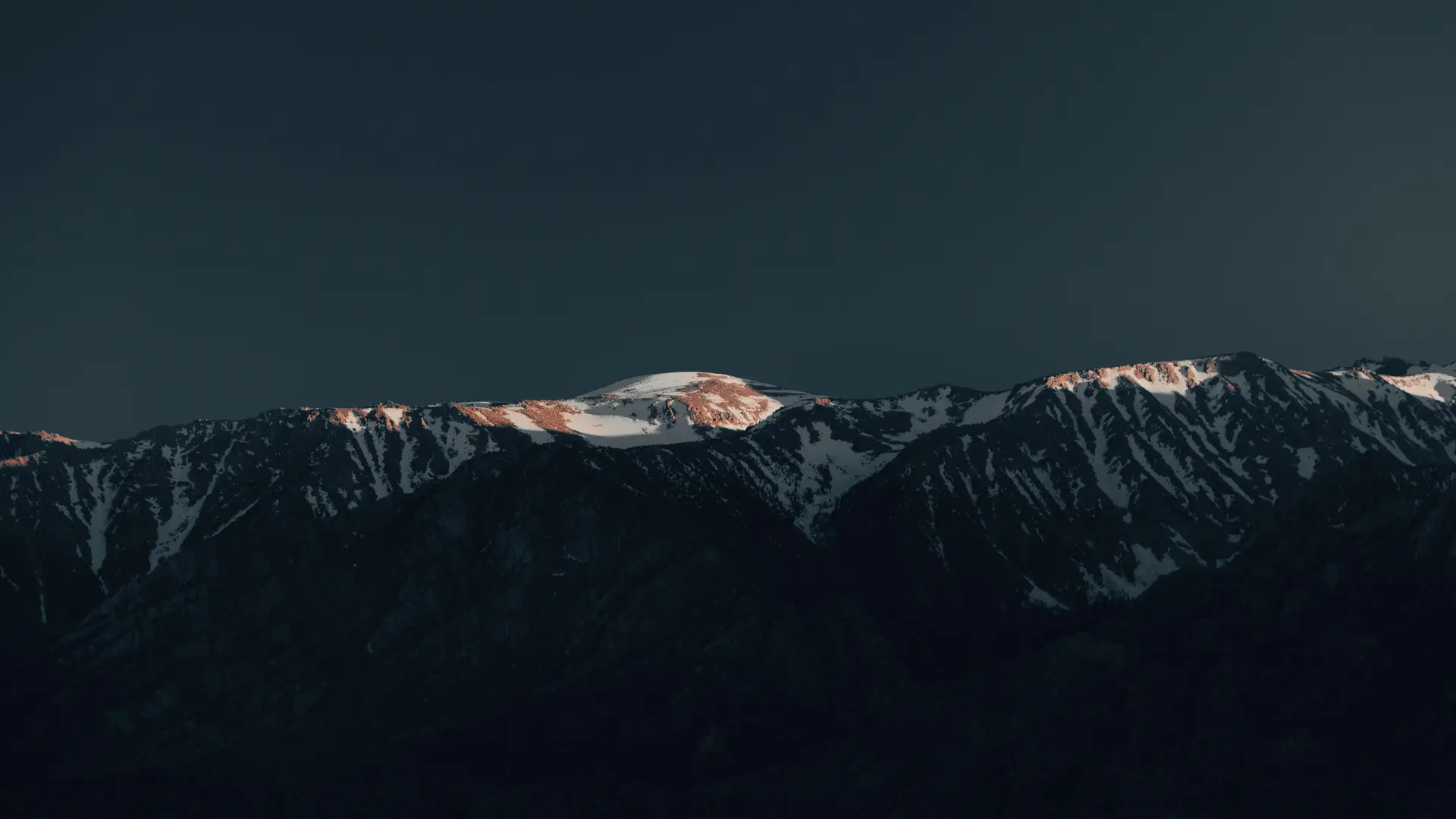 a_snowy_mountain_top_with_dark_sky.jpg