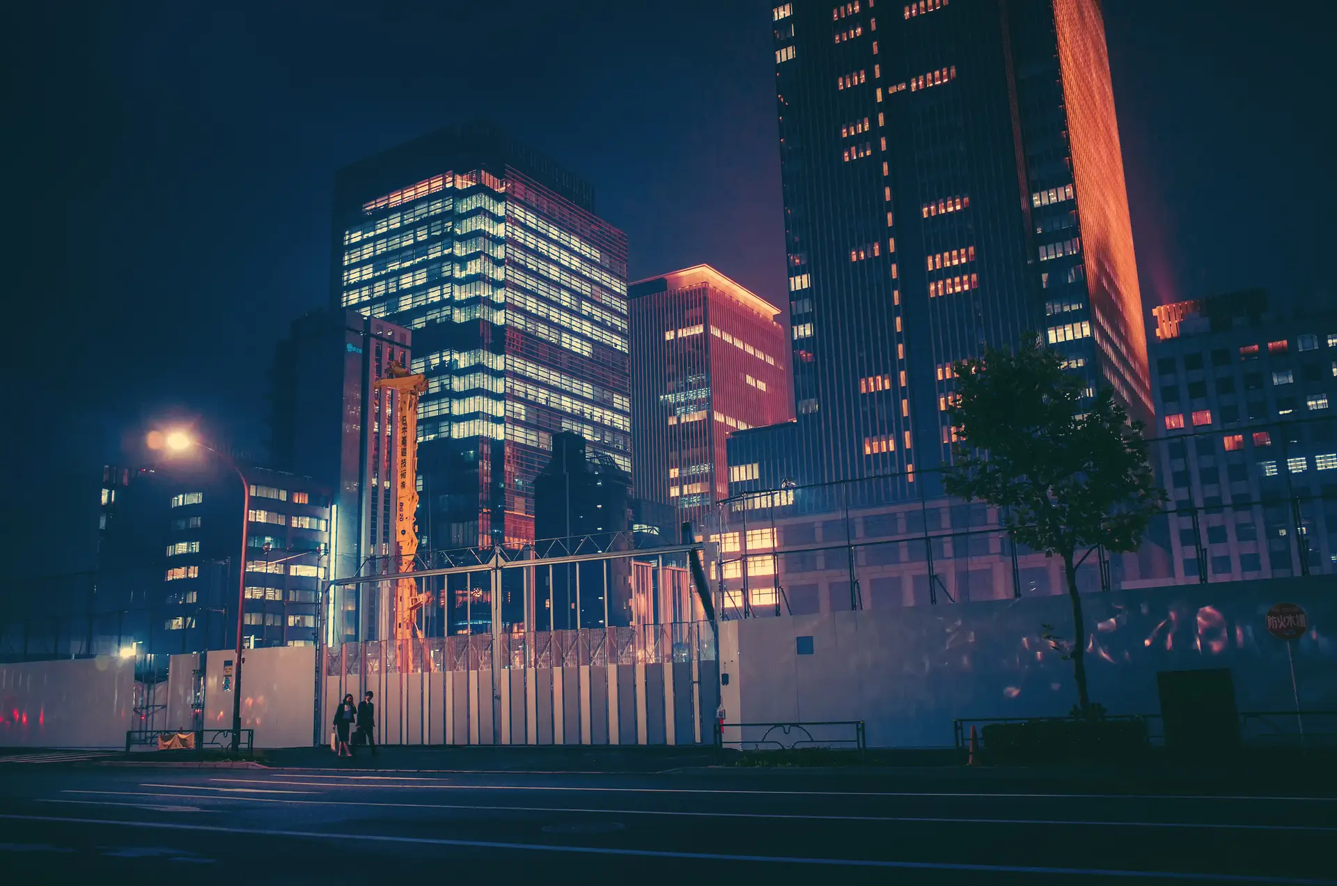 a_city_at_night_with_a_fence_and_buildings.jpg